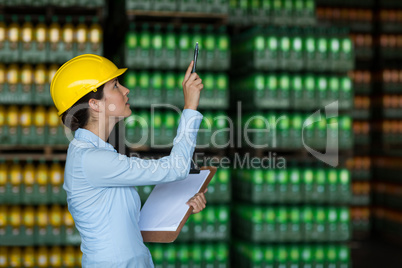 Female factory worker maintaining record on clipboard in factory