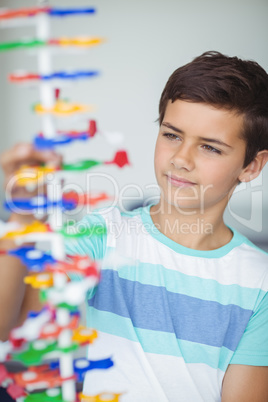 Attentive schoolboy experimenting molecule model in laboratory