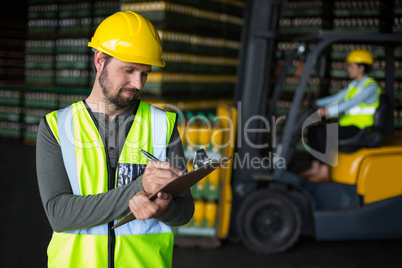 Factory worker writing on clipboard