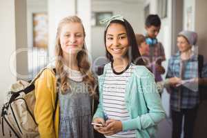 Portrait of smiling schoolgirls standing in corridor