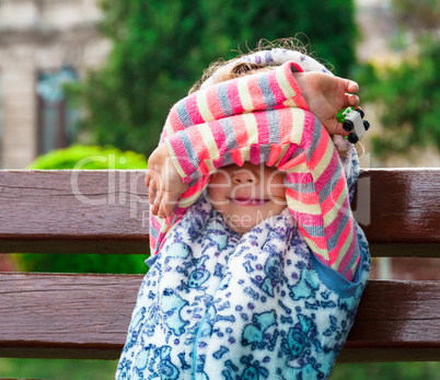 Little girl closes eyes with her hands.