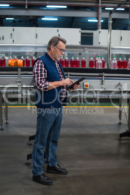 Factory worker using digital tablet next to production line