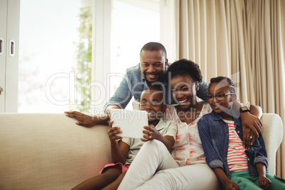 Parents and son using digital tablet on sofa in living room