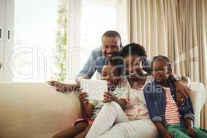 Parents and son using digital tablet on sofa in living room