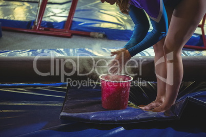 Female gymnast applying chalk powder on her hands before practicing