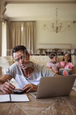 Portrait of man with laptop sitting in living room