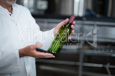 Factory worker examining a bottle in factory