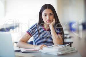 Portrait of sad schoolgirl sitting in classroom