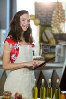 Female shop assistant using digital tablet at the counter in grocery shop