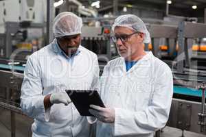 Two factory engineers discussing over digital tablet