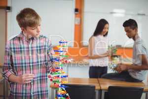Schoolboy examining the molecule model in laboratory