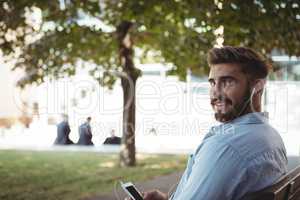 Executive listening music on mobile phone in park