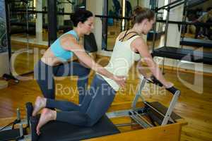 Female trainer assisting woman with stretching exercise