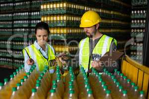 Two factory workers monitoring cold drink bottles