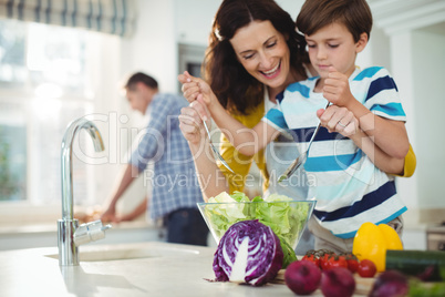 Mother and son mixing the salad in kitchen