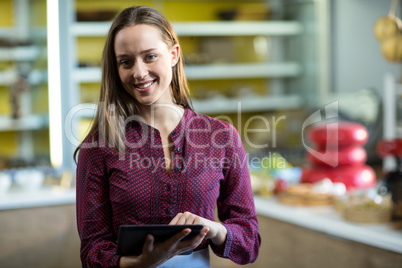 Portrait of smiling female staff using digital tablet at counter
