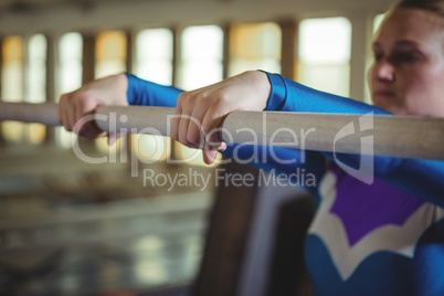 Female gymnast practicing gymnastics on the horizontal bar in the gymnasium