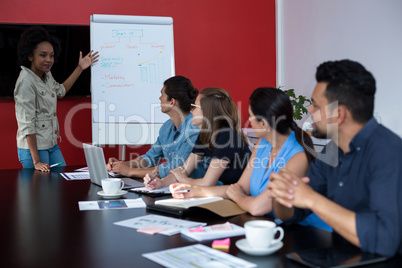 Business executives discussing over flip chart during meeting