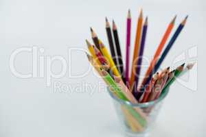 Colored pencils kept in glass on white background