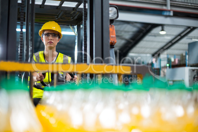 Female factory worker driving forklift in factory