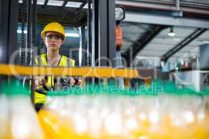 Female factory worker driving forklift in factory