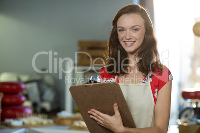 Female shop assistant writing on the clipboard at the counter