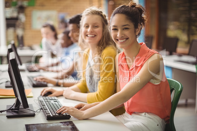 Portrait of smiling students studying in computer classroom