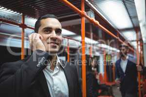 Executive talking on mobile phone in train