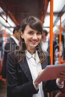 Smiling executive using digital tablet in train