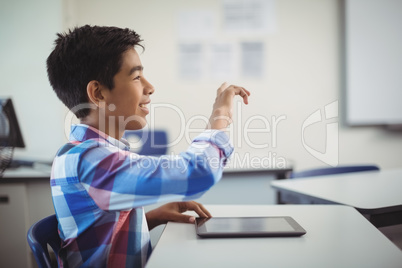 Schoolboy using digital tablet at desk