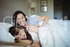 Mother and daughter laughing in bed