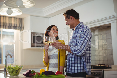 Happy couple toasting glasses of wine in kitchen