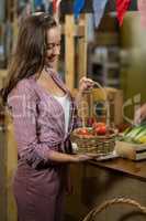 Smiling woman holding a basket of tomatoes