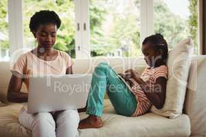 Mother and daughter using laptop and digital tablet