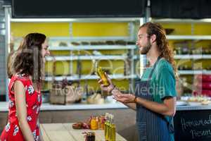 Shop assistant offering olive oil bottle to the customer