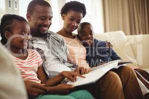Parents and kids sitting together on sofa with photo album