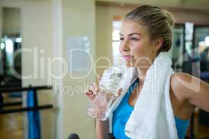 Thoughtful woman drinking water after workout
