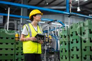 Female factory worker maintaining record on digital tablet