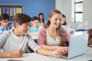 Students using digital tablet and laptop in classroom