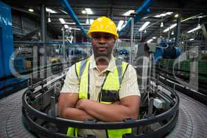 Confident factory worker standing near the conveyor belt