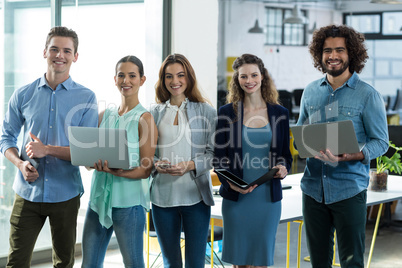 Business executives standing with digital tablet, mobile phone and laptop in office