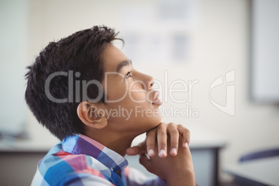 Thoughtful schoolboy sitting in classroom