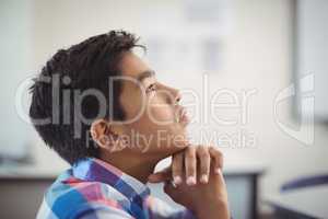 Thoughtful schoolboy sitting in classroom