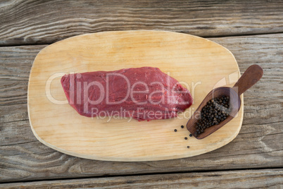 Beef steak and black pepper on wooden board