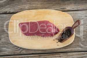 Beef steak and black pepper on wooden board