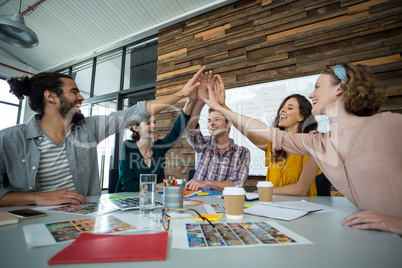 Graphic designers giving high five during meeting