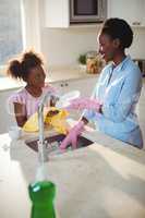 Mother assisting her daughter in cleaning utensils