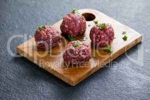 Minced beef garnished with coriander leaves on wooden board