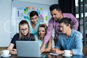 Businesspeople having discussion over laptop in office