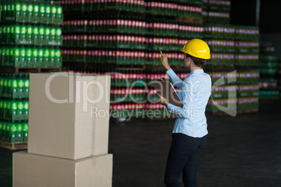 Female factory worker maintaining record on clipboard in factory